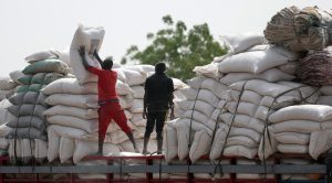 Bags of maize are offloaded from a truck at the market