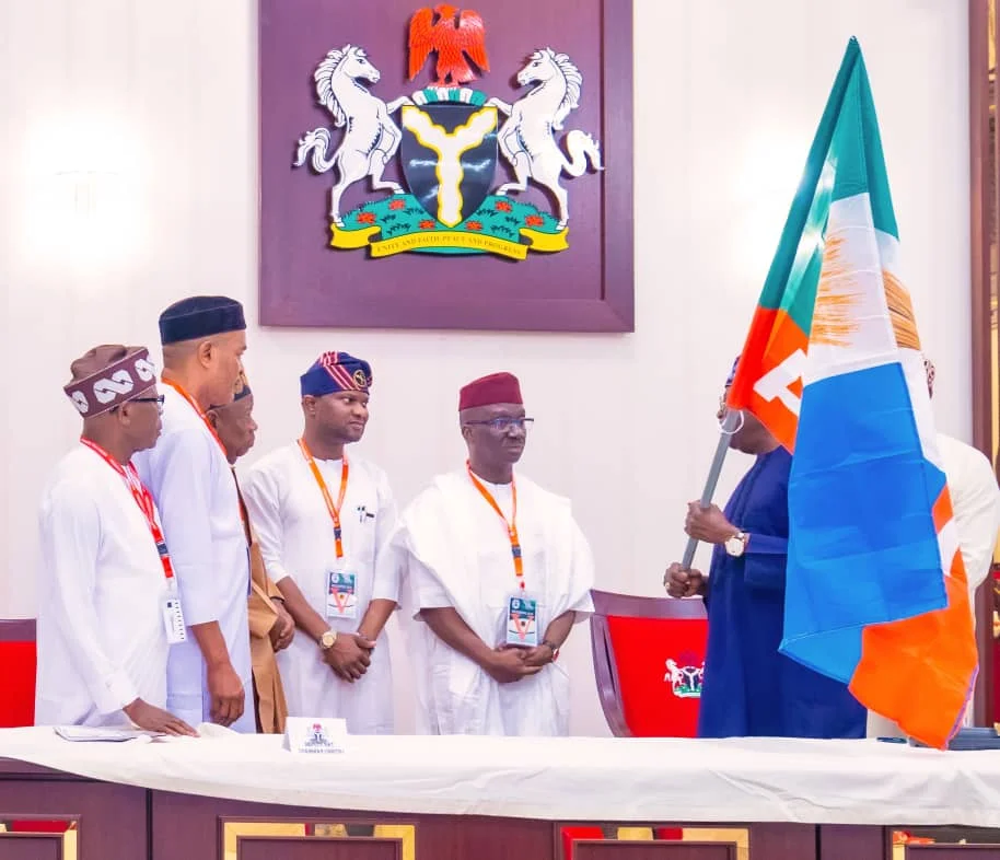 President Bola Tinubu presenting APC flag to the Edo governorship candidate, Sen. Monday Okpebholo, and his running mate, Dennis Idahosa on Monday in Abuja.