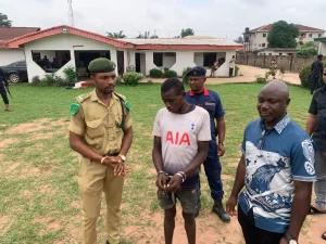 Re-arrested prison escapee, Chinonso Kalu (c) being handed over to the NCoS by the NSCDC in Owerri on Friday. (NAN PHOTO)