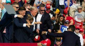 Republican candidate Donald Trump is seen with blood on his face surrounded by secret service agents as he is taken off the stage at a campaign event at Butler Farm Show Inc. in Butler, Pennsylvania, July 13, 2024. (Photo by Rebecca DROKE / AFP)