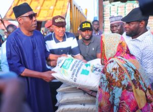 L-R Borno State Governor Babagana Umara Zulum assisted by Bakasi camp manager, Alhaji Grema Terab (2nd right), presenting a relief package to the victim of the Maiduguri flood disaster (1st right).