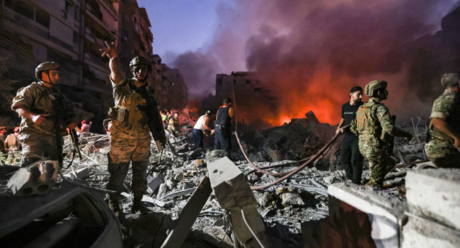 Lebanese army soldiers gather over the rubble of a levelled buildings as people flight the flames, following Israeli air strikes in the Haret Hreik neighbourhood of Beirut’s southern suburbs on September 27, 2024. (Photo by Ibrahim AMRO / AFP)