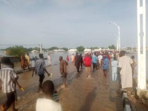Residents moving through a flooded bridge in Maiduguri on Wednesday.