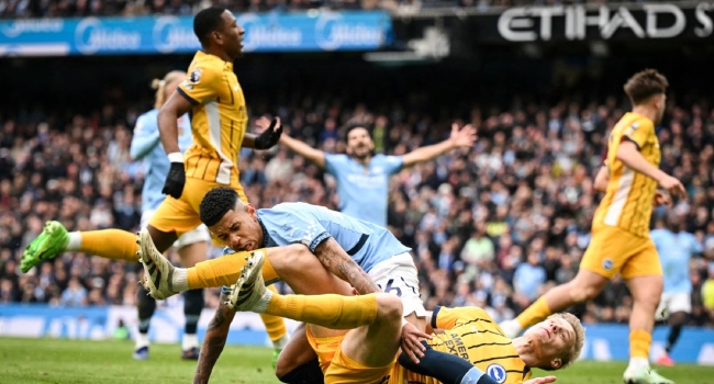 Manchester City’s Brazilian midfielder #26 Savinho (up) collides with Brighton’s Dutch defender #29 Jan Paul van Hecke as he shoots the ball and misses to score during the English Premier League football match between Manchester City and Brighton and Hove Albion at the Etihad Stadium in Manchester, north west England, on March 15, 2025. (Photo by Oli SCARFF / AFP)