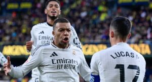 Real Madrid’s French forward #09 Kylian Mbappe celebrates with teammates Real Madrid’s Spanish defender #17 Lucas Vazquez (R) and Real Madrid’s English midfielder #05 Jude Bellingham (L) after scoring their second goal during the Spanish League football match between Villarreal CF and Real Madrid CF at La Ceramica Stadium in Vila-real on March 15, 2025. (Photo by JOSE JORDAN / AFP)