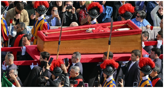 Pallbearers, next to Swiss Guards, carry the coffin of the late Pope Francis (C) as it is transported from the chapel of Santa Marta to St Peter’s Basilica, following the Pope’s death, in the Vatican on April 23, 2025. (Photo by Alberto PIZZOLI / AFP)