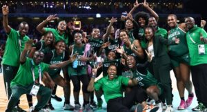 Nigeria’s players and staff, with Nigeria’s US coach Rena Wakama (3rdR) pose as they celebrate after winning the women’s preliminary round group B basketball match between Canada and Nigeria during the Paris 2024 Olympic Games at the Pierre-Mauroy stadium in Villeneuve-d’Ascq, northern France, on August 4, 2024. (Photo by Sameer AL-DOUMY / AFP)