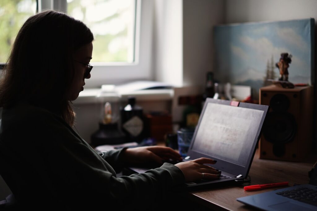 A woman sitting at a desk, focused on her laptop, exploring the concept of AI enablement.
