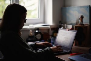 A woman sitting at a desk, focused on her laptop, exploring the concept of AI enablement.