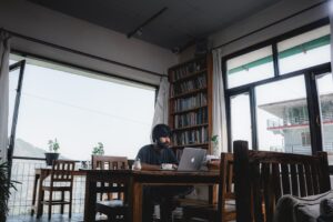 A man sitting at a table with a laptop, focused on analyzing AI enablement performance indicators and ROI.