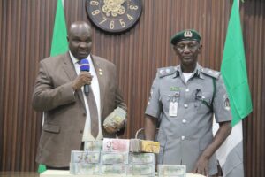 Customs Area Controller for Kano/Jigawa Area Command, Comptroller Dalhatu Abubakar, handling over the seized foreign currency to the EFCC Zonal Director of Kano Command