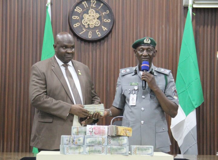 Customs Area Controller for Kano/Jigawa Area Command, Comptroller Dalhatu Abubakar, handling over the seized foreign currency to the EFCC Zonal Director of Kano Command