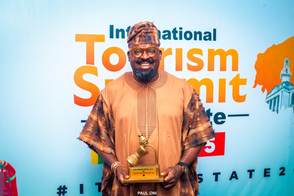 Kunle Afolayan displayimg his Tourism Entrepreneur of the Year Award during the Oyo international summit